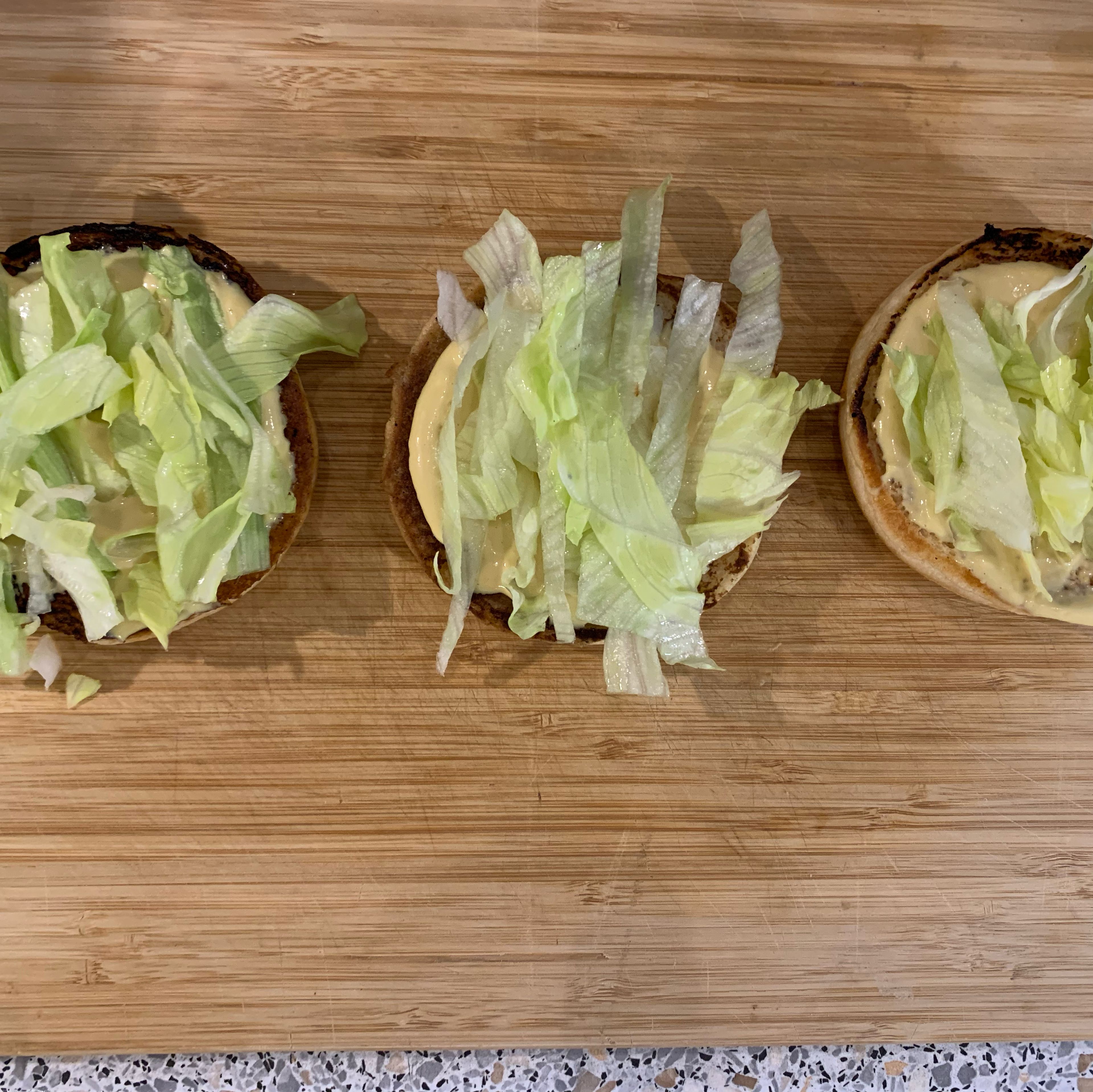 Die Mayo-Senf-Mischung auf den Boden des Burgerbrötchens geben und den Salat darüber legen.