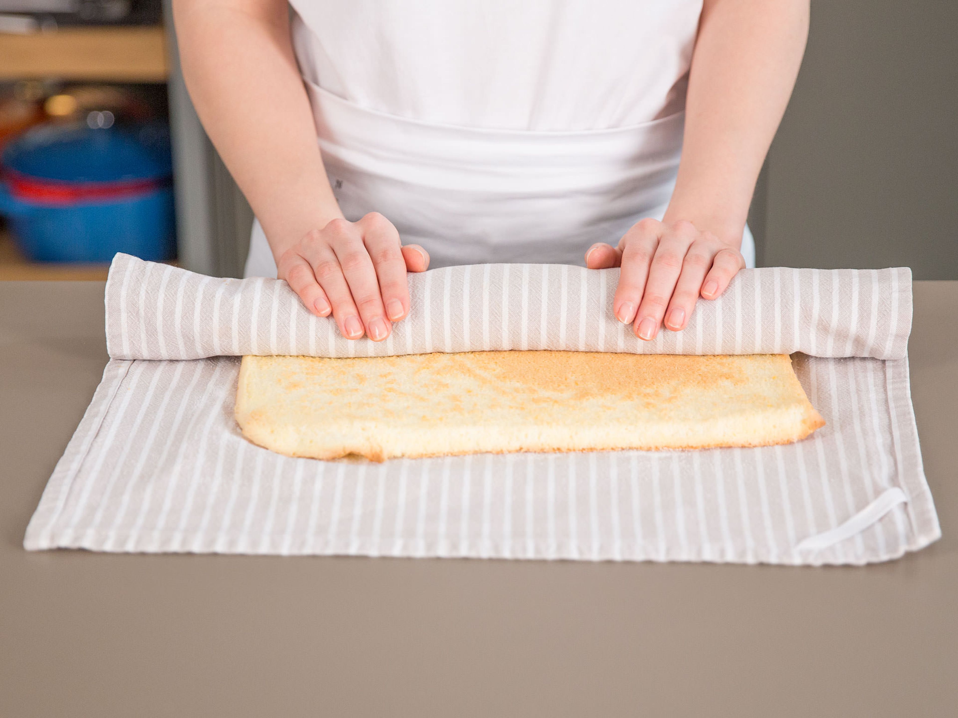 Etwas Zucker auf ein sauberes, leicht feuchtes Küchentuch streuen. Kuchen darauf platzieren und Backpapier entfernen.