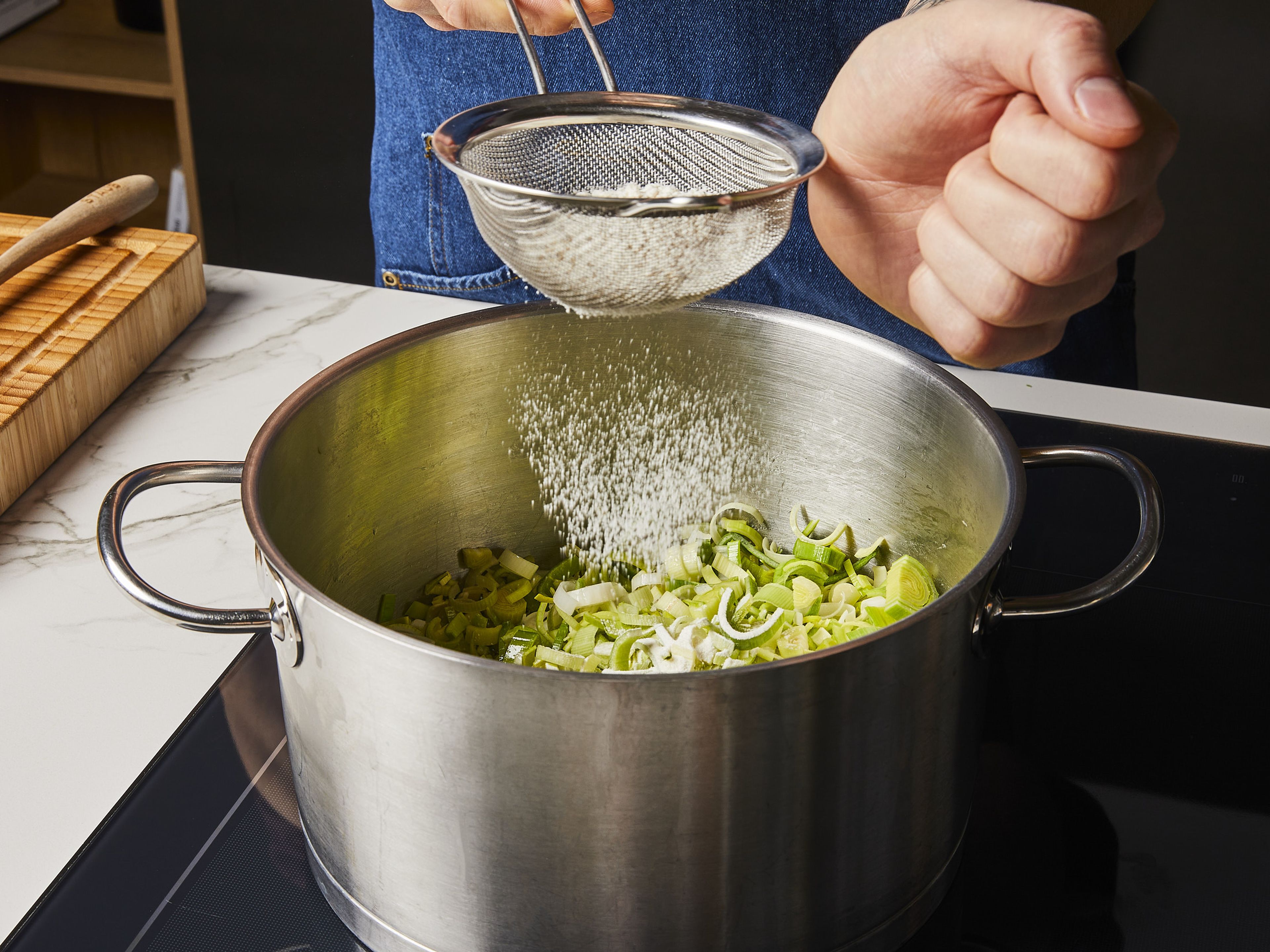 Heat oil in a pot over medium heat. Add the chopped green beans and leeks to the hot pot and fry for approx. 2–3 min., without letting them take on any color. Sift the flour over the vegetables and mix everything well.