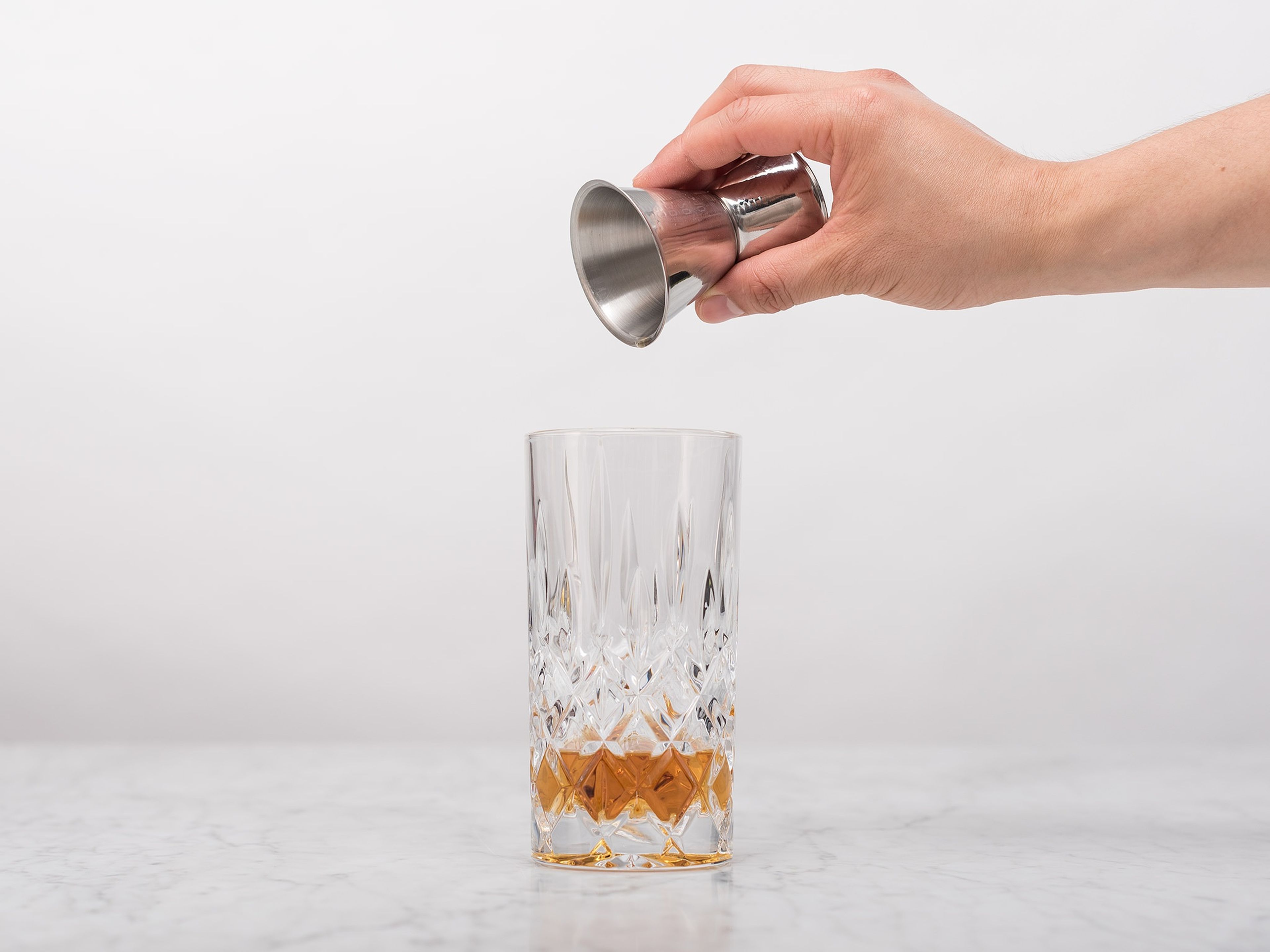 Pour whiskey into a highball glass.