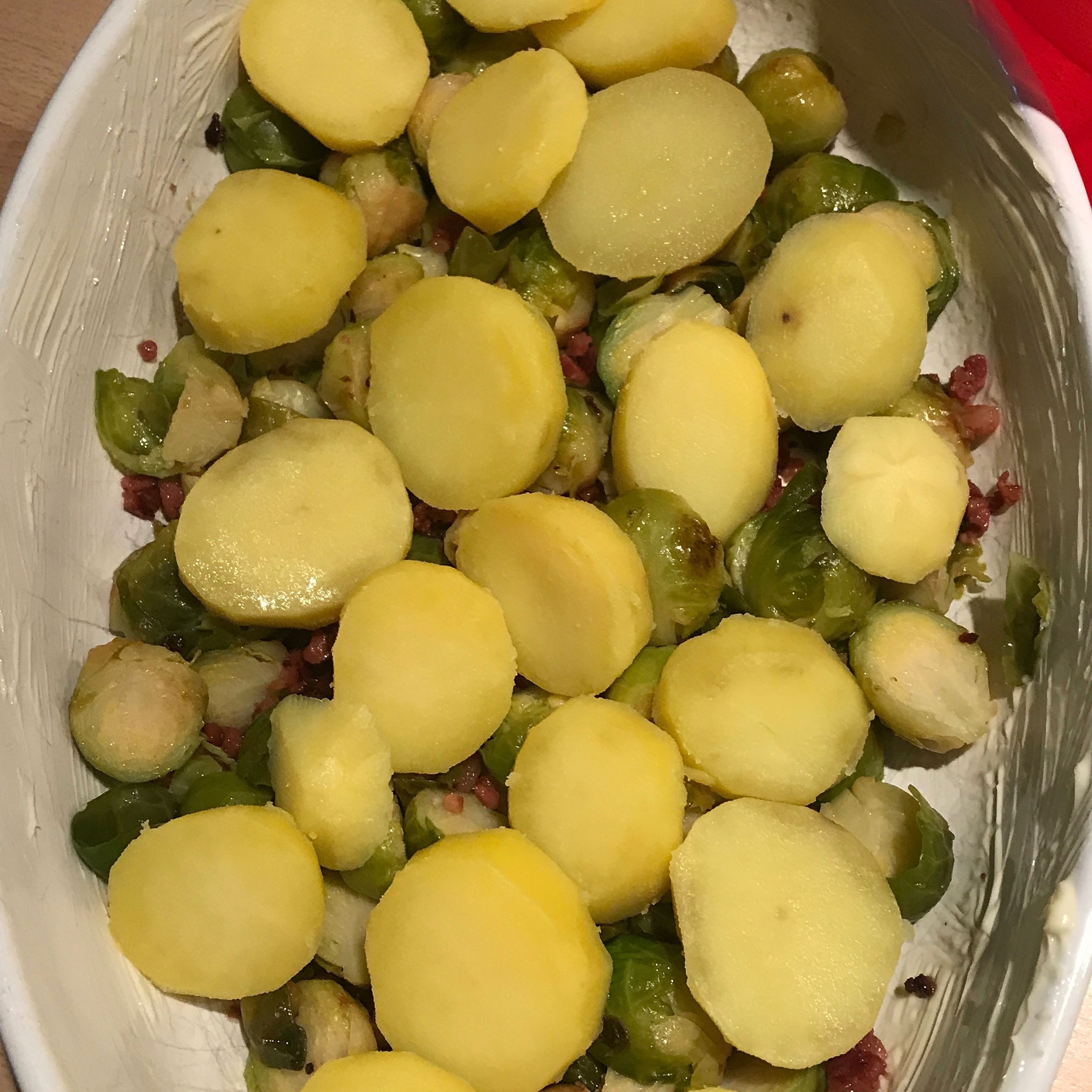 Die Kartoffeln und den Rosenkohl in der eingebutterten Auflaufform verteilen und die Sauce darüber verteilen.