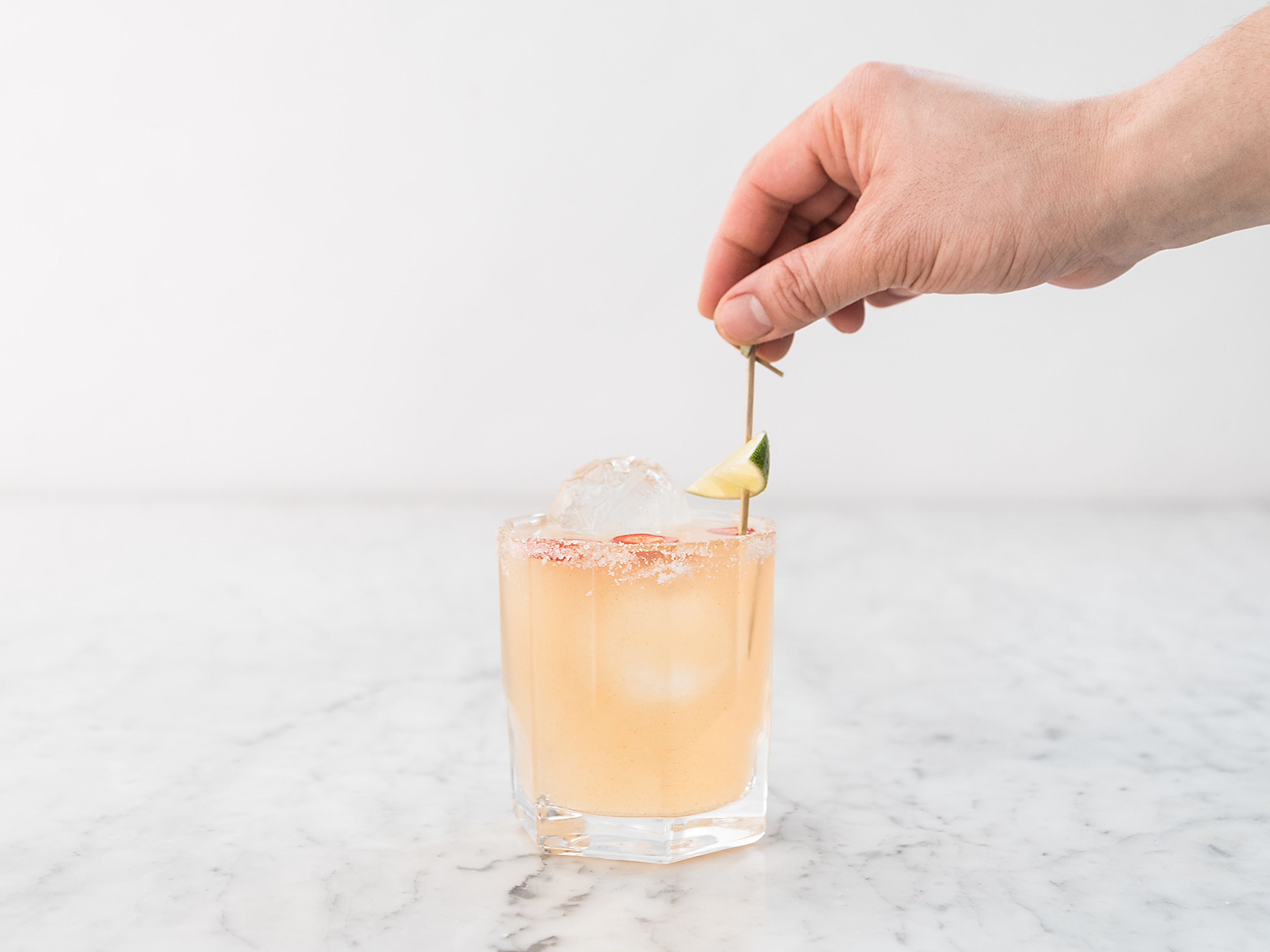 Strain into an ice filled, salt rimmed cocktail glass. Garnish with chili rings and a lime wedge. Enjoy!