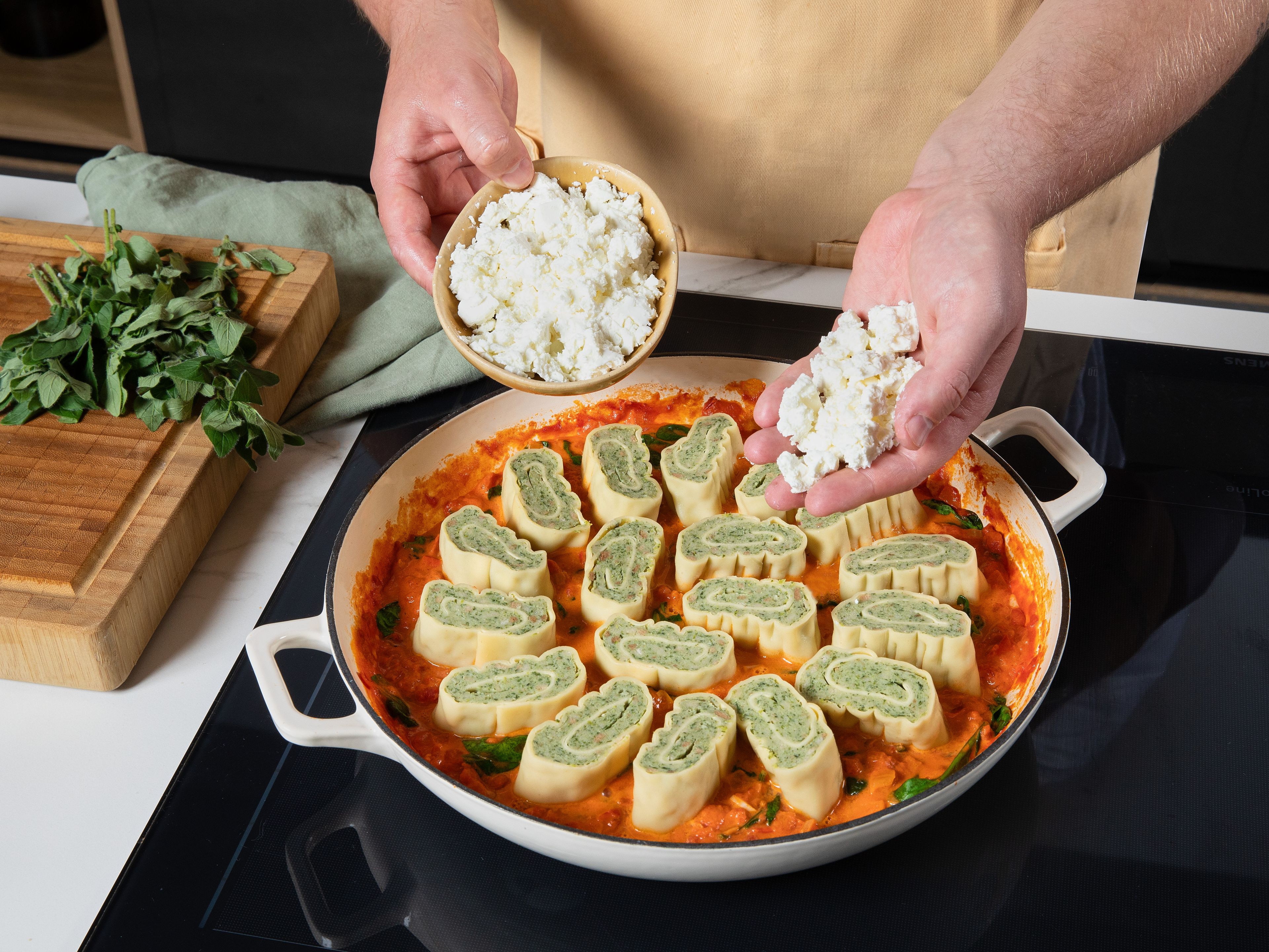 Feta grob zerbröseln und gleichmäßig über den Auflauf streuen. Den Auflauf im vorgeheizten Ofen ca. 30 Min. goldbraun backen, bis die Soße blubbert und der Feta leicht gebräunt ist. Vor dem Servieren kurz ruhen lassen, den frischen Oregano von den Stielen zupfen und darüber verteilen.
