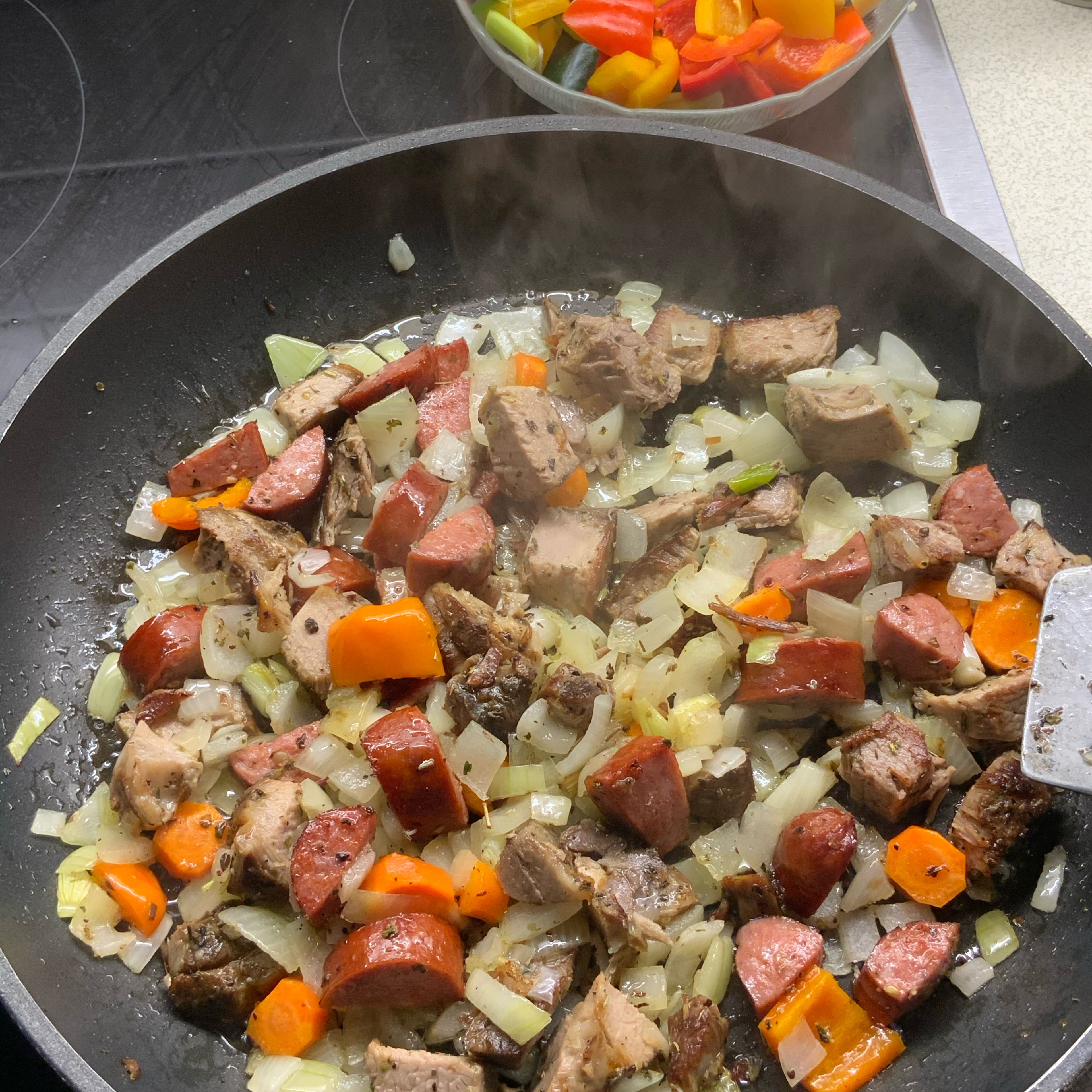 Nach 3-4 Minuten Zwiebel, Karotten, Braten- und Cabanossistücke in der Pfanne vermengen....