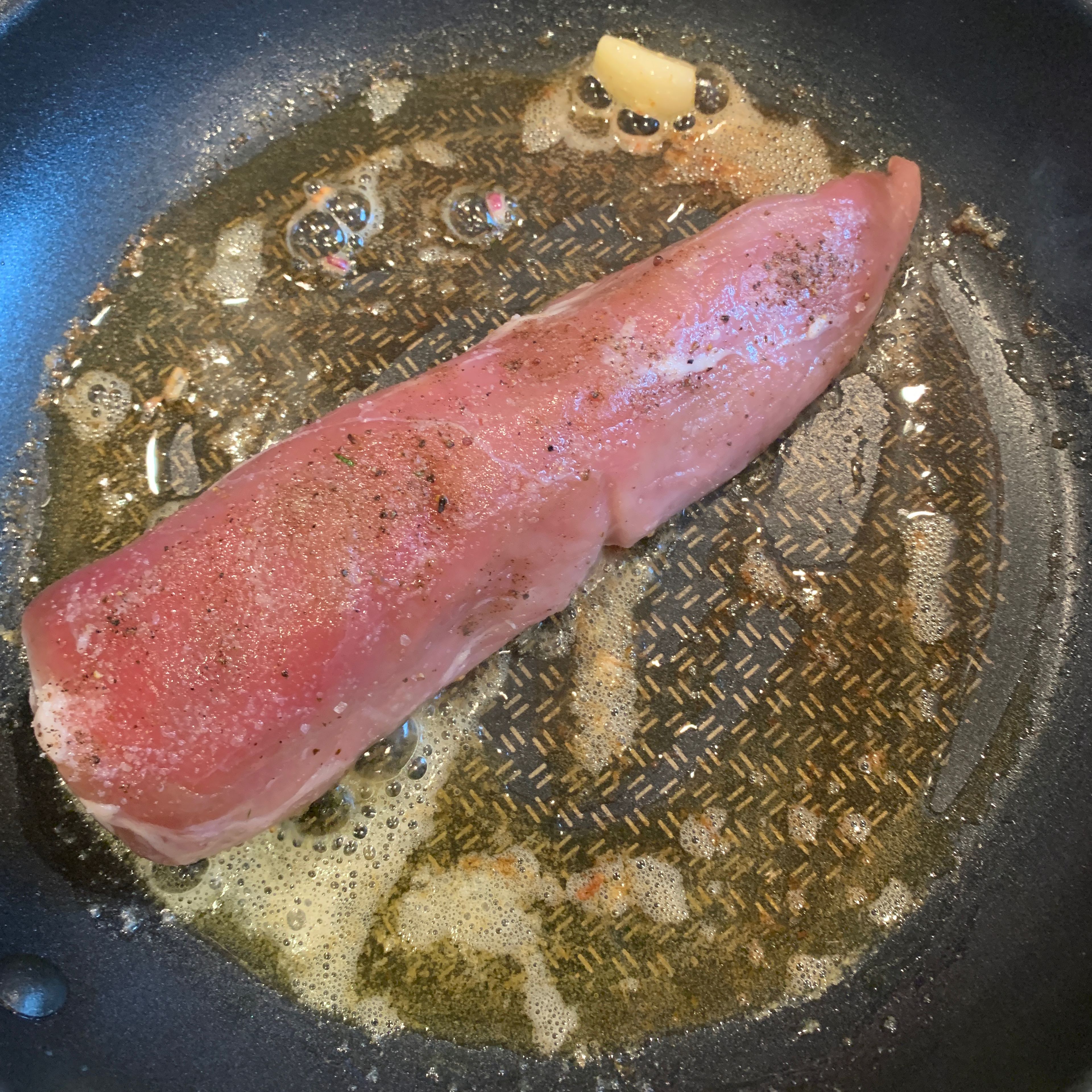 Schweinefilet salzen und pfeffern und Butter in einer Pfanne mit der Knoblauchzehe erhitzen. Das Nudelwasser aufsetzen. Das Schweinefilet von allen Seiten scharf anbraten.