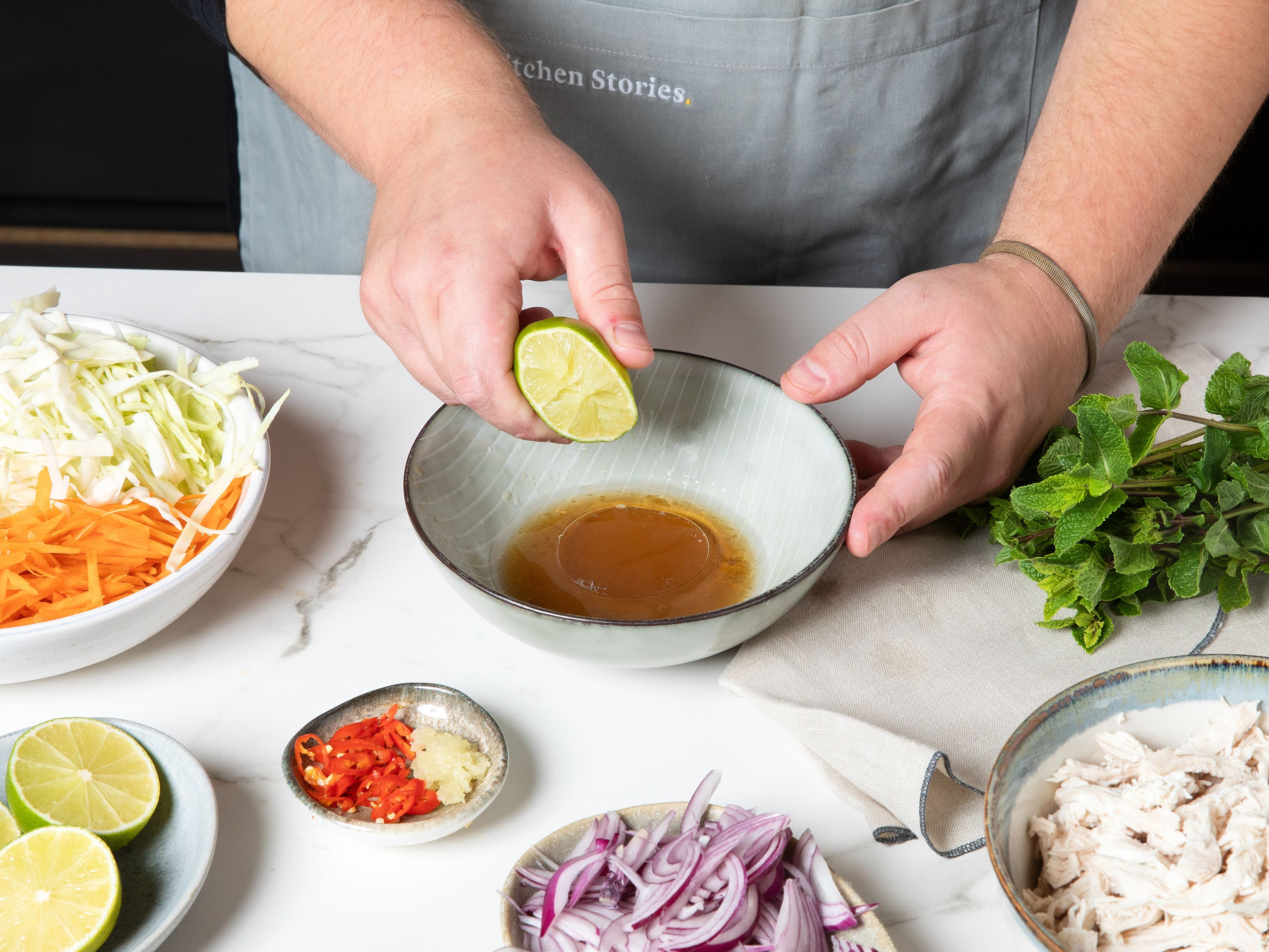 Cut cabbage, carrots, and onions into fine strips. Finely chop chili and garlic. For the dressing whisk together white wine vinegar, sugar, fish sauce, chili, garlic, and lime juice in a small bowl. Combine all ingredients in a large bowl, mix well, and gently massage the dressing into salad with your hands.